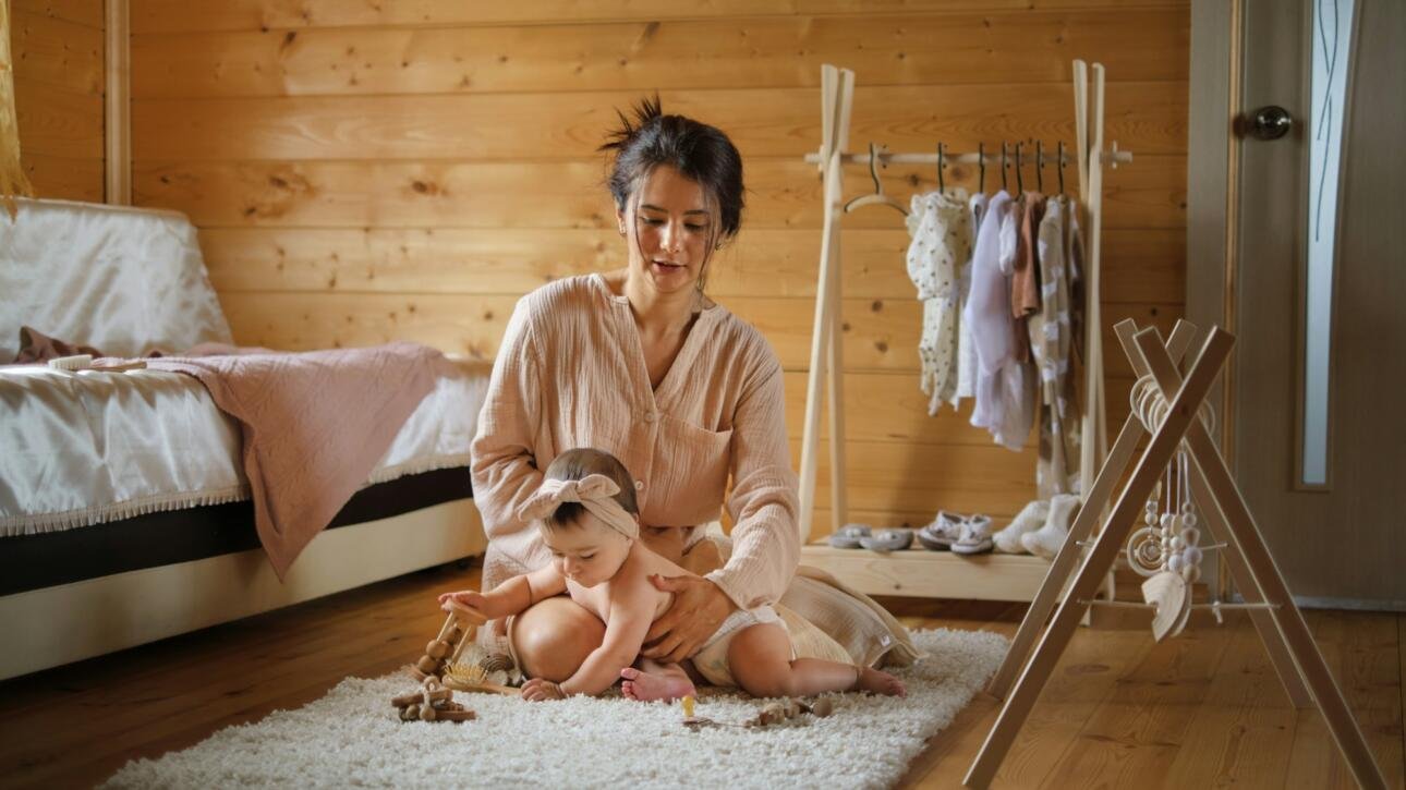 Careful hands guide a baby into clothes, amidst a rustic room. This picture celebrates the intimacy