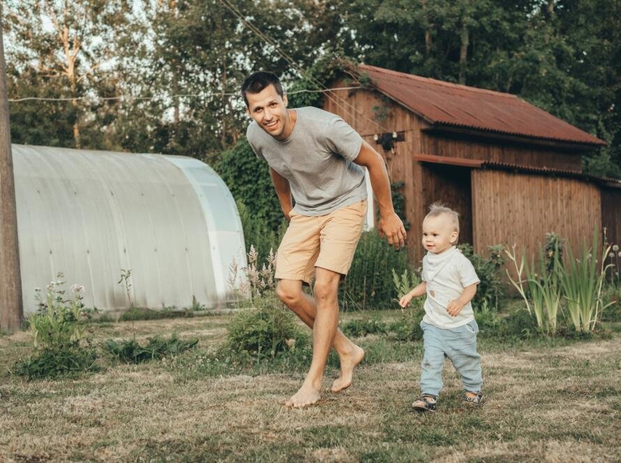 Dad and little daughter run across the lawn.