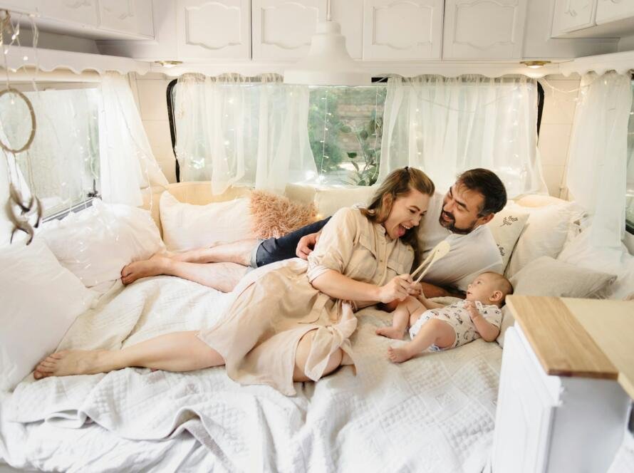 Family with baby on the bed in trailer in the morning.