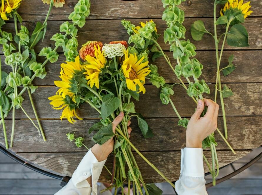 Florist at work. Woman making beautiful bouquet of different flowers. Workplace. Top view