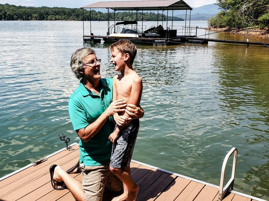 Grandpa letting his grandkid know that the lake water is not that cold and he should jump.