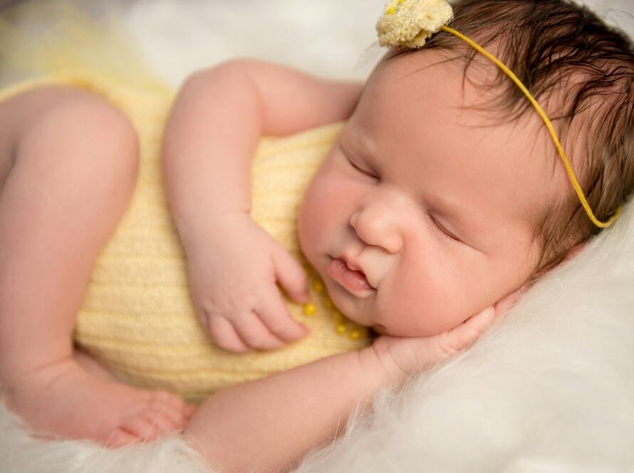 lovely baby in yellow romper sleeping with legs crossed