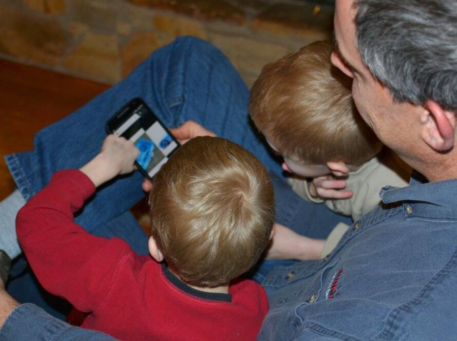 Man showing children how to use a smart phone