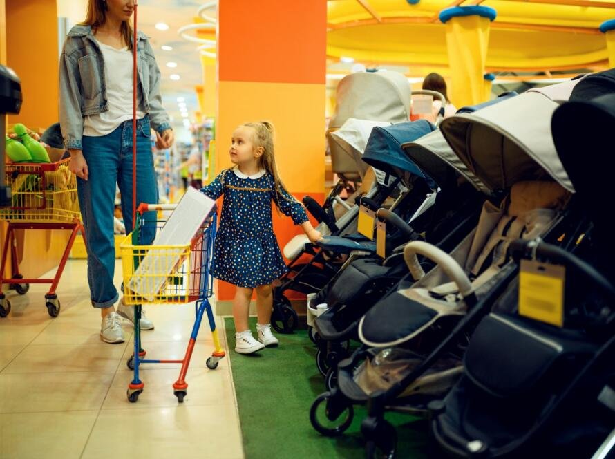 Mother and little girl buying baby stroller