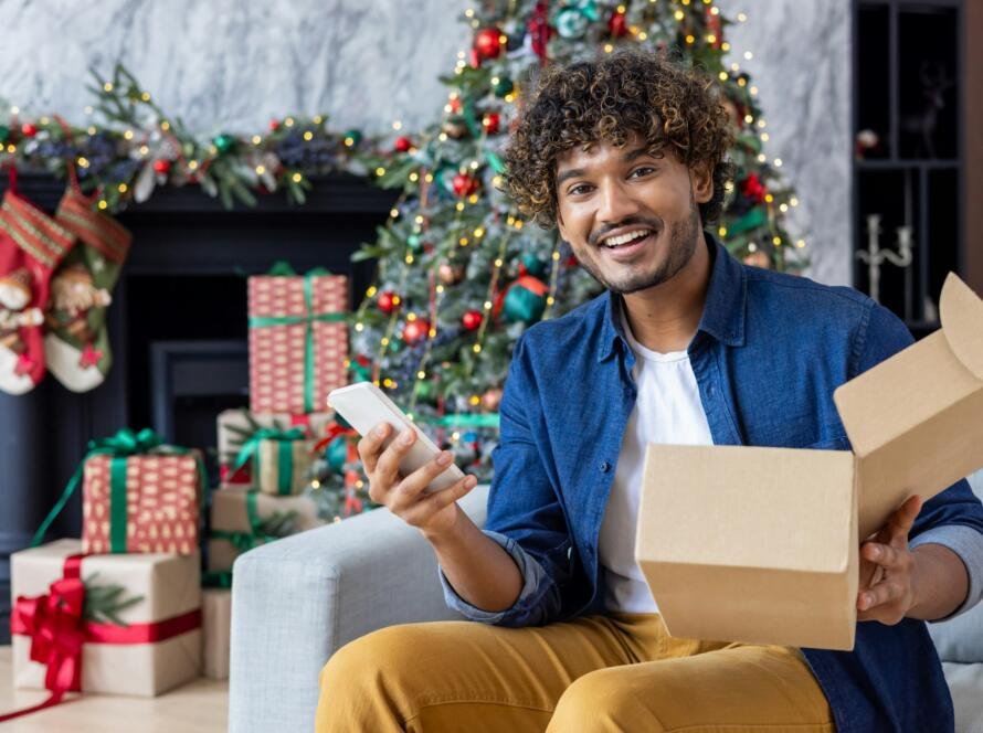 Portrait of a happy buyer in online store, a man smiles and looks at the camera, holds a phone and