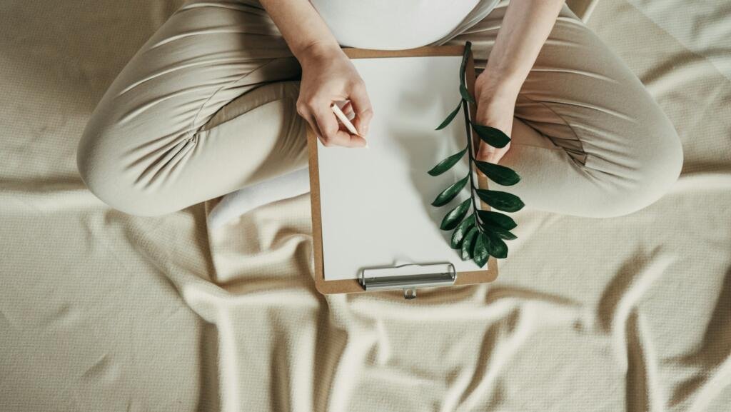 Pregnant woman writing baby names list at home.