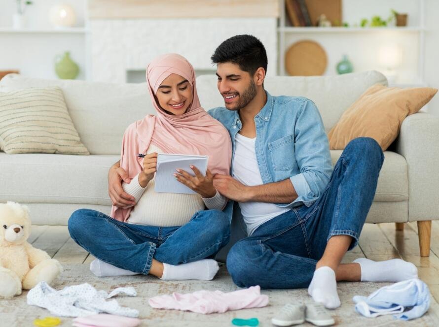 Preparing for childbirth. Pregnant muslim couple making checklist of baby things before going to