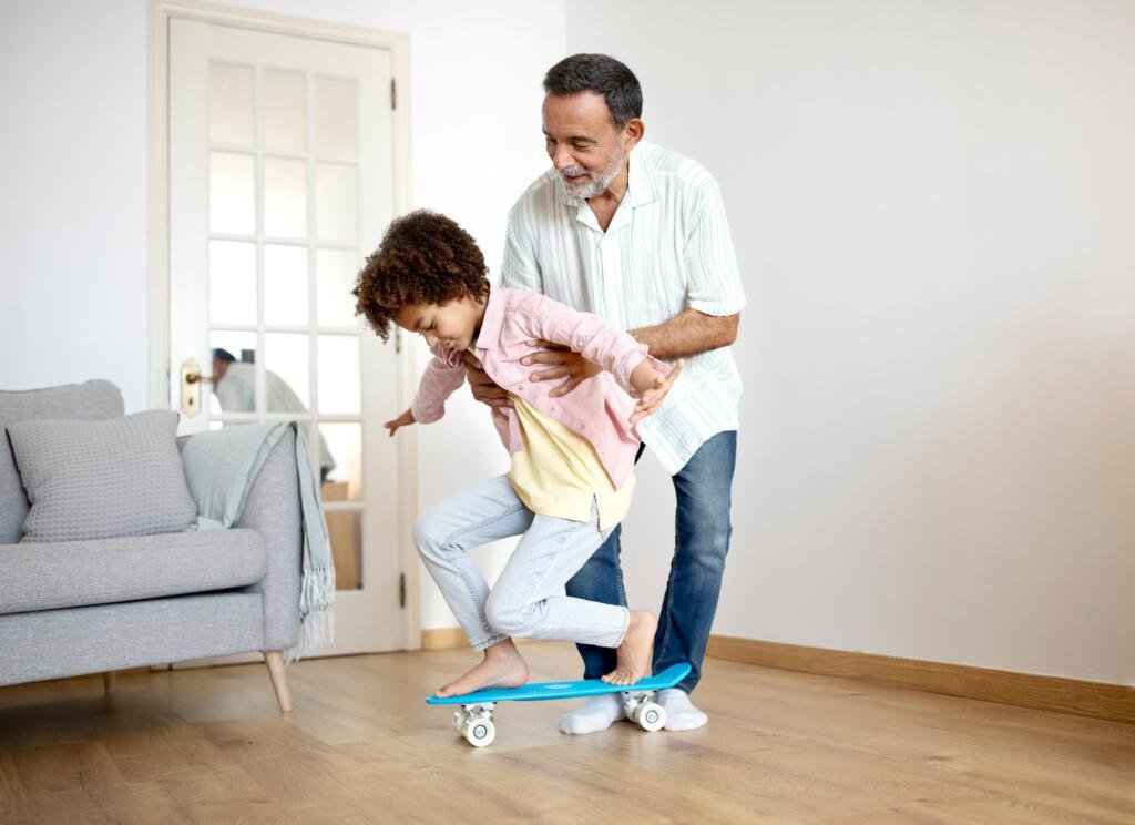 Smiling Latin Grandfather Guides Grandson's First Skateboard Ride at Home