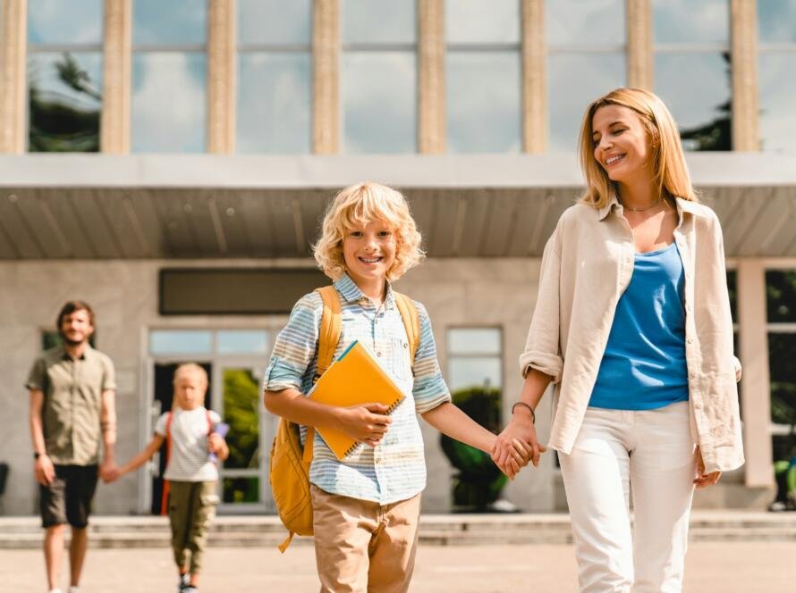 Young parents escorting their kids children from school home after lessons classes