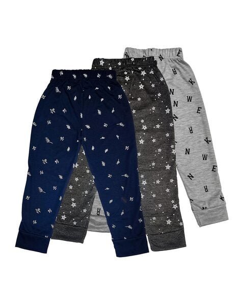 Three pairs of children's pyjama bottoms with elastic waistbands: one navy with white patterns, one dark grey with stars, and one light grey with black letters.