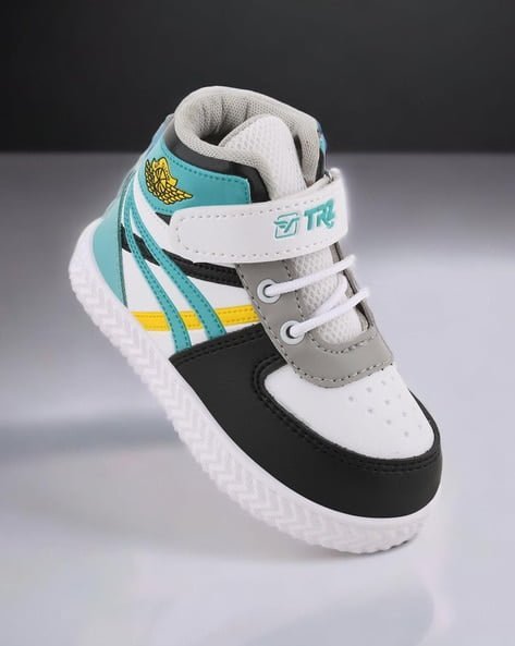 High-top sneaker with teal, yellow, and black details, featuring a wing logo and TR text on the strap.