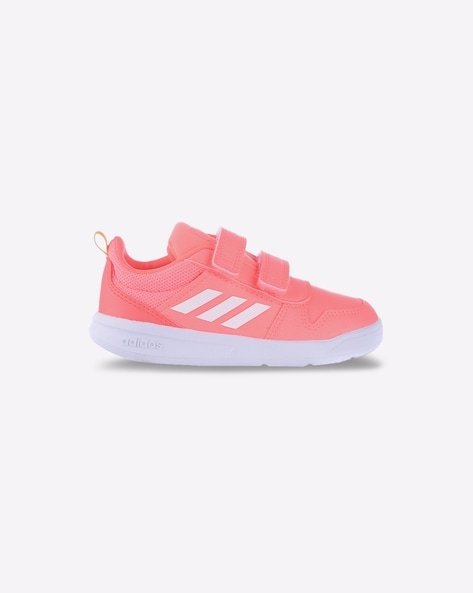 Pink children's trainer with white sole, two velcro straps, and white branded stripes on the side.