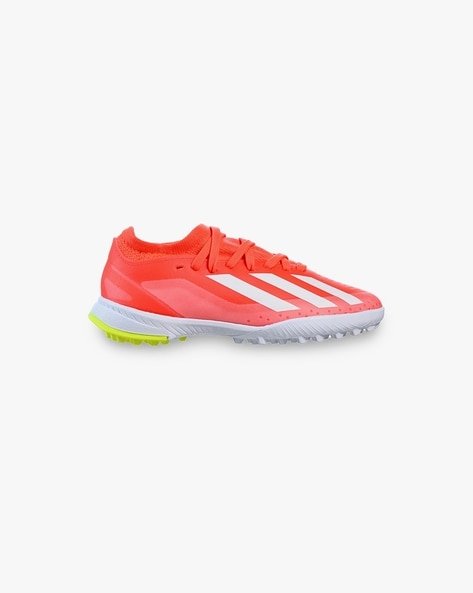 A red and white athletic shoe with a textured sole and neon yellow accents.