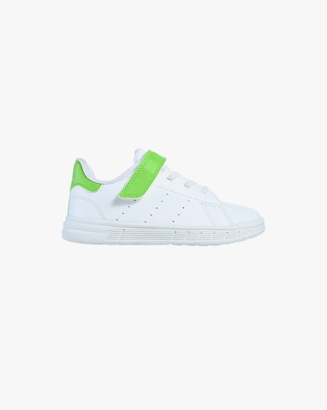 White sneaker with green accents and Velcro strap.